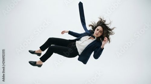 Businesswoman Falling in Air Against a Soft White Background with Hair and Suit Flowing Gracefully