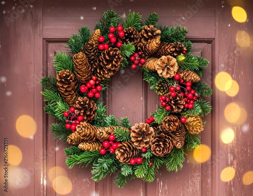 Evergreen wreath with red berries and warm bokeh lights.
