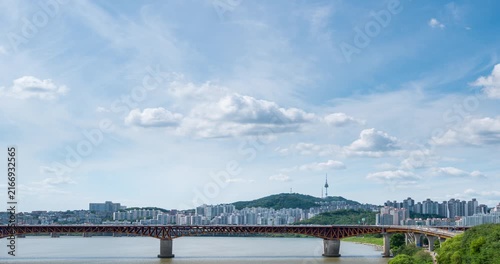 4kTime lapse. The Han River in Seoul, South Korea, during the day, revealing a bright blue sky and traffic on the bridge spanning the river.