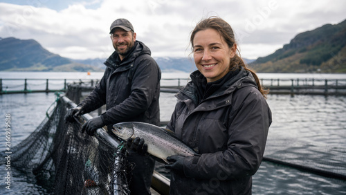 Fishermen holding salmon at fish farm