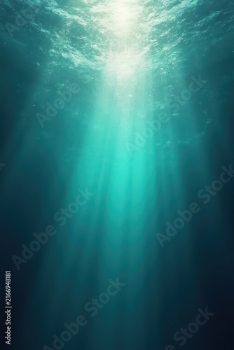 Underwater scene with sunlight streaming through rippling surface, blending turquoise and deep blue tones into darker depths, evoking serene ethereal ocean atmosphere.