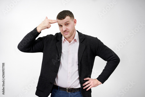 Canvas Print man pointing his finger to his head to shoot himself on a gray background, stres