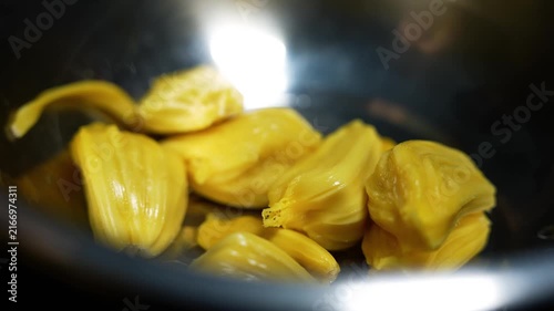 Close up of ripe jackfruit pieces in a dark bowl with soft light reflection