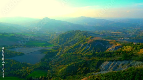 Refreshing aerial push-in truck right pan left shot near Santa Vittoria in Matenano, mystical sunlight imbuing the horizon with a hazy, mysterious quality, spiritual views of Sibillini Mountains peaks
