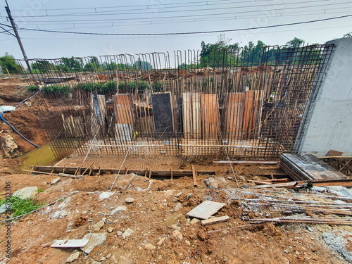 Construction site featuring steel reinforcement bars and wooden formwork for a concrete foundation wall.
