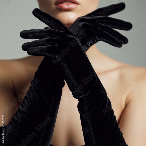 woman wearing long black velvet gloves with arms crossed in front of her face