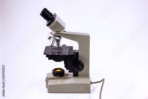 Classic binocular laboratory microscope with rotating objective turret, mechanical stage, focusing controls and built-in illumination, isolated against a clean white background.