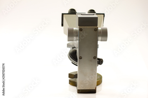 Rear view of a vintage binocular microscope with precision focusing controls, metal housing and sturdy circular base, isolated against a clean white background.