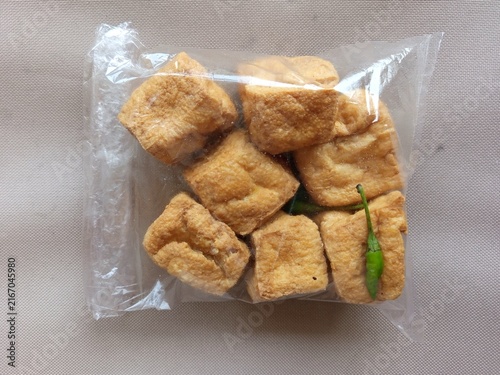 Konstfotografi Indonesian traditional fried tofu called Tahu Sumedang with green cayenne pepper in a plastic bag wrap