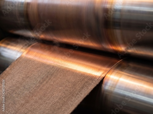 A calender nip pressing a sheen onto passing cloth
