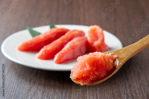 Fresh tarako roe on wooden spoon with plated portions in white dish