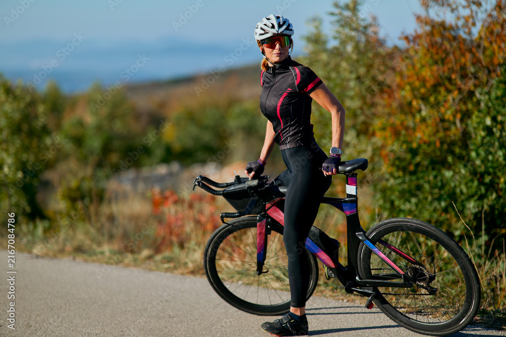 Fototapeta premium Female Cyclist With Triathlon Bike Wearing Helmet and Sunglasses Training Outdoors on Country Road