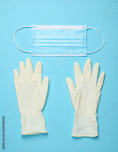 Medical face mask and protective gloves on blue background