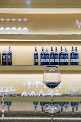 Glass of Red Wine on Bar Counter with Backlit Bottle Display