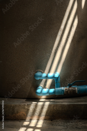 Water Storage Tank with Blue PVC Pipes and Sunlight Shadows