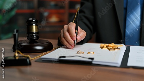Attorney signs legal agreement detailing asset division, executing official divorce settlement papers beside legal gavel as formal settlement resolves marital property settlement.