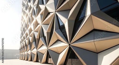 Modern architectural facade with geometric triangular patterns and metallic panels on a building exterior.