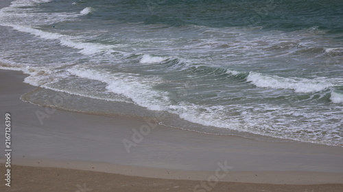 Fotografía The image depicts a calm shoreline where gentle waves are rolling onto a sandy beach
