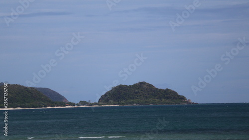 The image depicts a coastal scene with a large body of water in the foreground, showing gentle waves and a calm surface