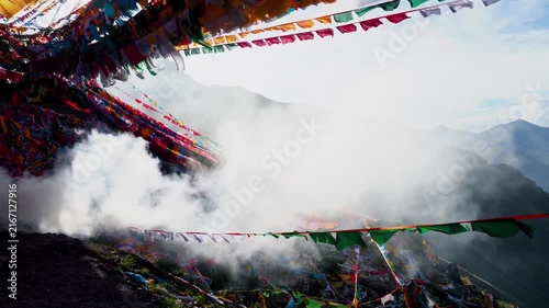 Tibetan prayer flags and incense smoke over mountain valley, sacred highland religious scenery, Sichuan China