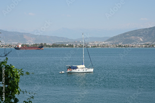 A white sailing yacht sails through a dark blue bay