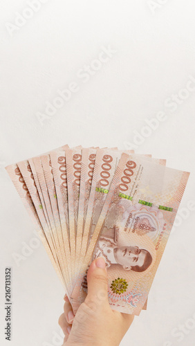 Hand holding 1000 Thai Baht banknotes on white wall background. Business and finance concept.
