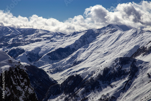 Snowy mountain peaks under blue sky with clouds, winter Caucasus landscape view