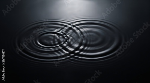 Circular water ripples merging on dark surface in concentric patterns abstract liquid splash effect black background