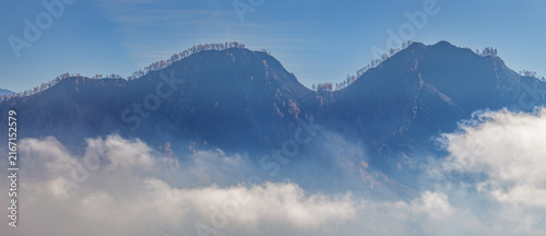 Mountains in the morning haze, peaks above the clouds, panoramic