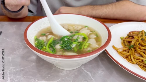 Close Up of Chinese Wontons on Restaurant Table – Traditional Dumpling Soup with Green Onions