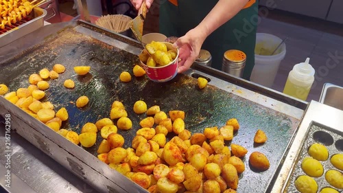 Korean Street Food – Frying Potato Slices with Red Chili Pepper on Hot Griddle at Outdoor Market