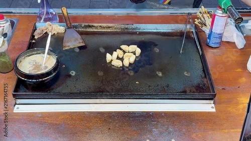 Korean Street Food,Myeong Dong  – Frying Potato Slices with Red Chili Pepper on Hot Griddle at Outdoor Market