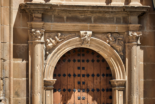 Bild auf Leinwand Historic arched wooden doorway framed by carved stone columns, capitals and figu