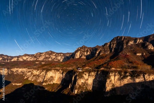 Star trails over rugged mountain cliffs at night