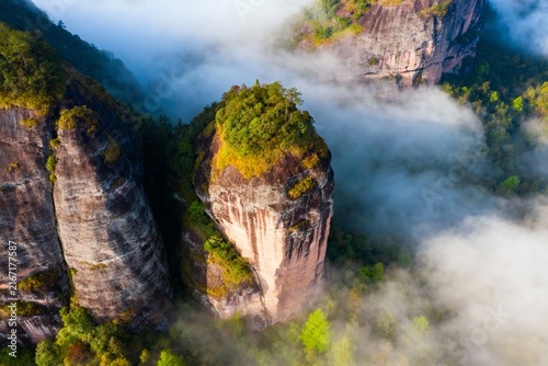 Aerial view of mist-covered rock formations with lush green vegetation in a mountainous landscape