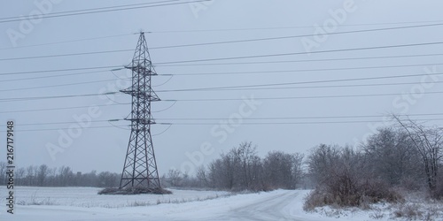 Photography High-voltage power transmission pylon in a snowy industrial landscape