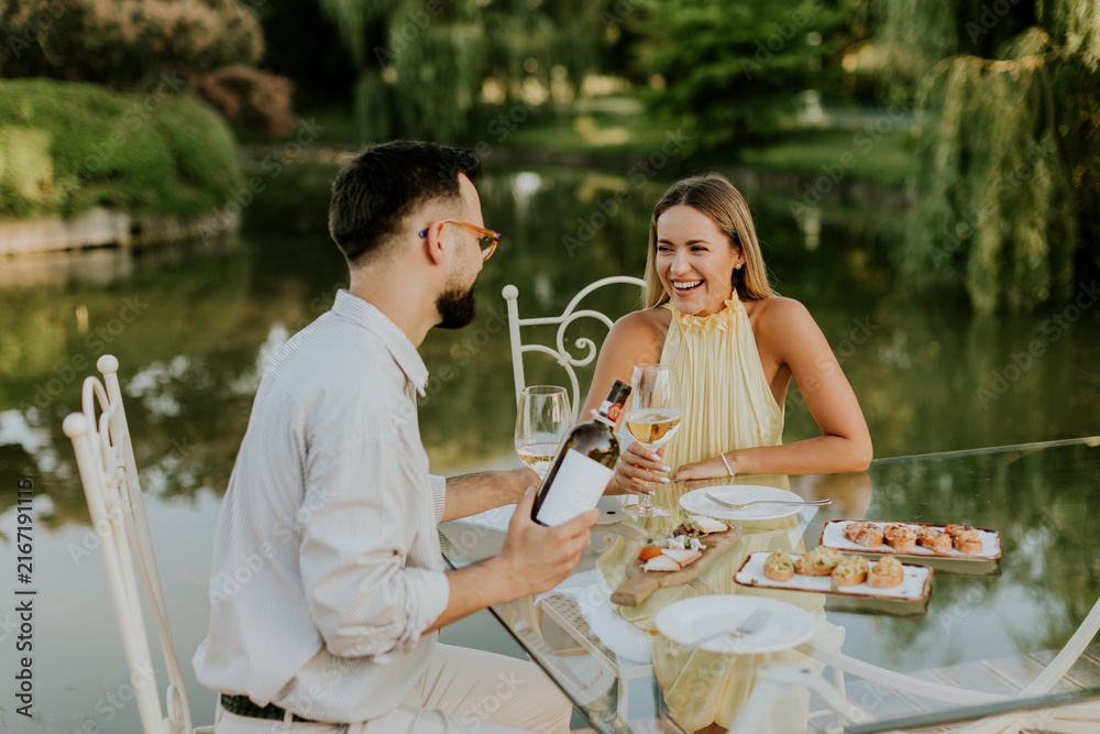 Fototapeta premium Couple having a lovely picnic by the serene lake at sunset