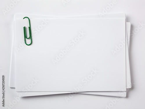 Stack of blank white paper sheets with a green paperclip on a clean white background