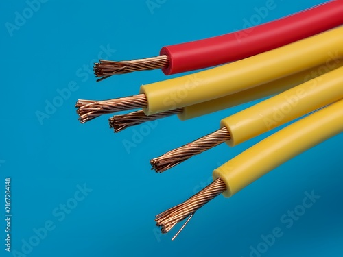Stripped electrical copper wires with red and yellow insulation on blue background