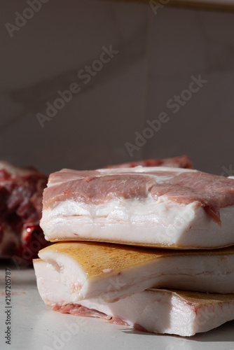 Raw pork belly slabs on cutting board in home kitchen, documentary realism of meat handling