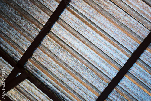 Canvas Print Abstract view of corrugated metal roofing beneath dark structural beams, featuri