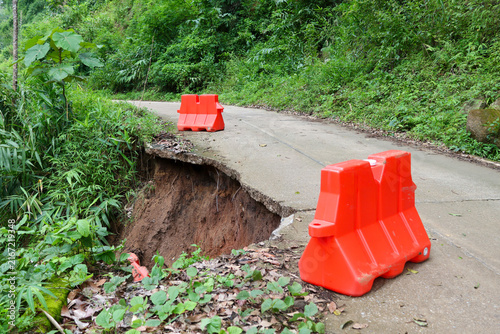 Canvas Print Orange barrier concrete road landslide damage tropical vegetation, showing dange