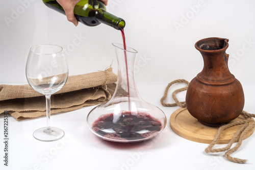 фотографія Hand pouring red wine from bottle into glass decanter