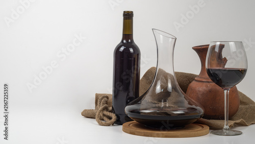 Foto Red wine bottle, decanter and glass with rustic clay jug