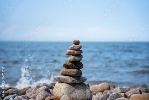 Canvas Print Stacked smooth stones balanced on pebbles by the calm sea