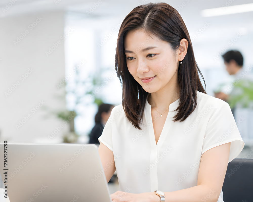 Fototapeta premium Smiling Japanese businesswoman working on laptop in bright modern office with copy space