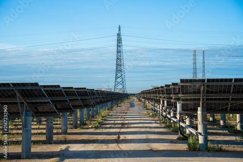 Solar Power Farm With Transmission Towers Under Clear Sky
