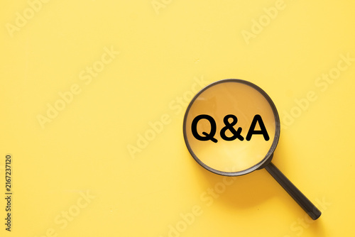 Cuadro en lienzo Top view of a magnifying glass focusing on the text Q&A on a yellow background with copy space