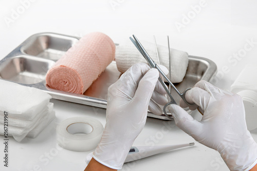 Fotografía Medical first aid supplies with bandages, gauze, scissors, forceps, gloves, and thermometer prepared for wound care and healthcare treatment on a clean white background