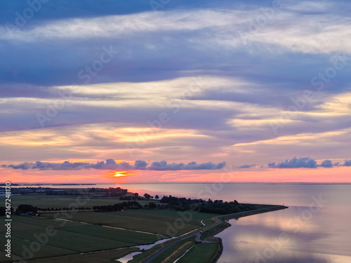 Foto Cinematic aerial view of a green Dutch dike and coastal road during a dramatic s